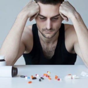 Despairing man in front of pills needs to detox from percocet