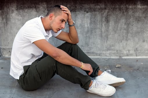 Despairing young guy surrounded by cement also surrounded by alcoholism.