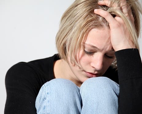 Curled up young woman may be going through the stages of alcohol detox.