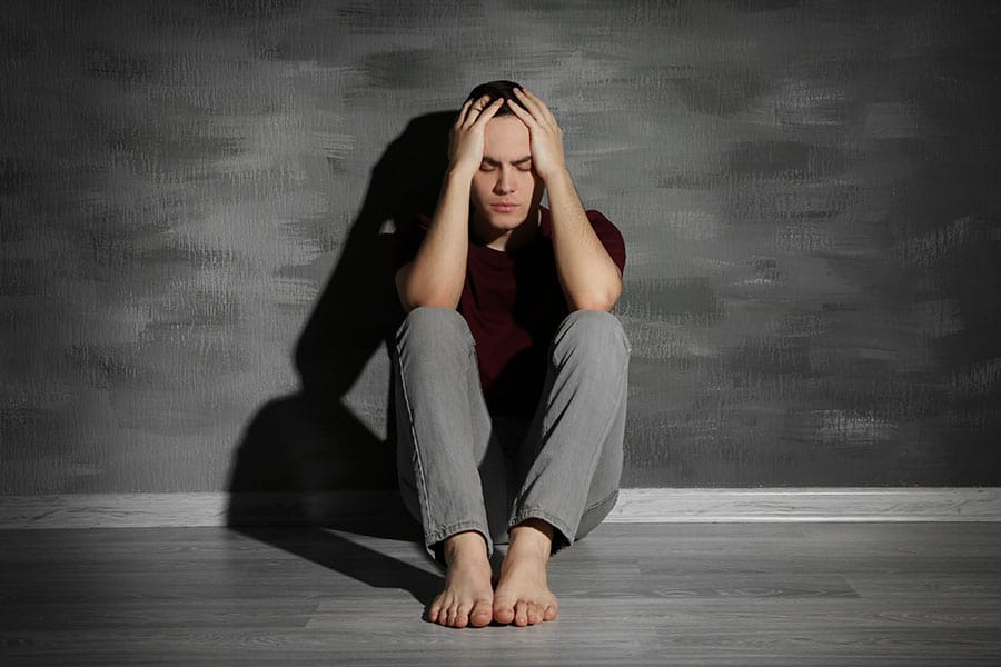 Depressed guy against wall may benefit from addiction rehab