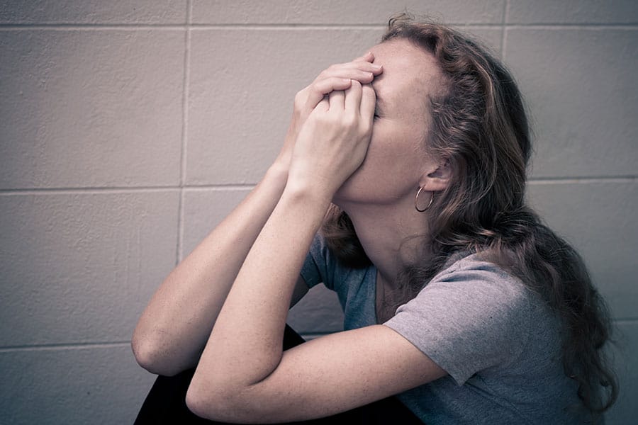 Woman covering her face needs one of the drug rehab centers in Florida to ger sober.