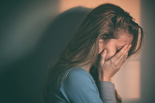 Sad woman with face in hands wondering how to deal with her latest drug overdose.