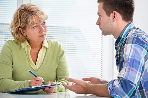 Counselor and young man chatting before inpatient alcohol detox treatment.