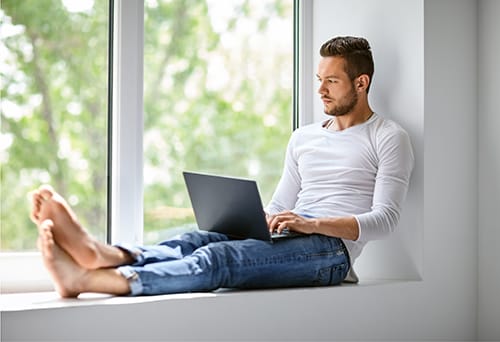 Man sitting in window with laptop during downtime at morphine detox center