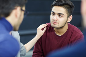 person consoling a man in group therapy at a schizophrenia treatment center